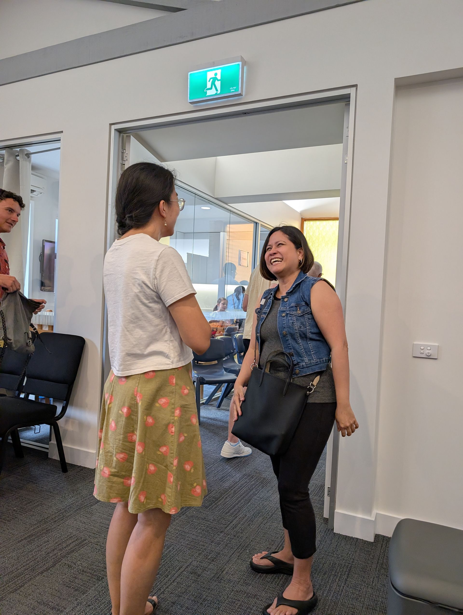 Two women laughing and greeting each other at church